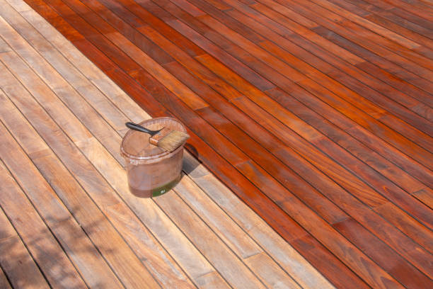 Freshly stained wood deck with rich finish and staining supplies, showcasing deck staining by a painter in Natick, MA